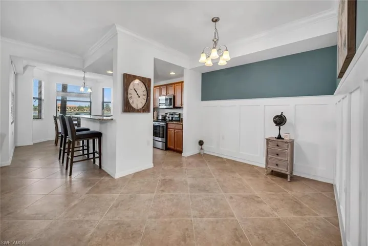 Kitchen with appliances with stainless steel finishes, hanging light fixtures, crown molding, and a chandelier