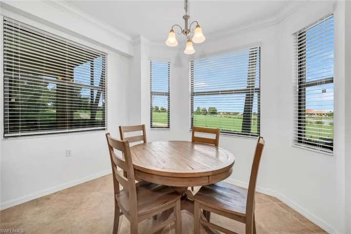 Tiled dining space featuring ornamental molding and a chandelier