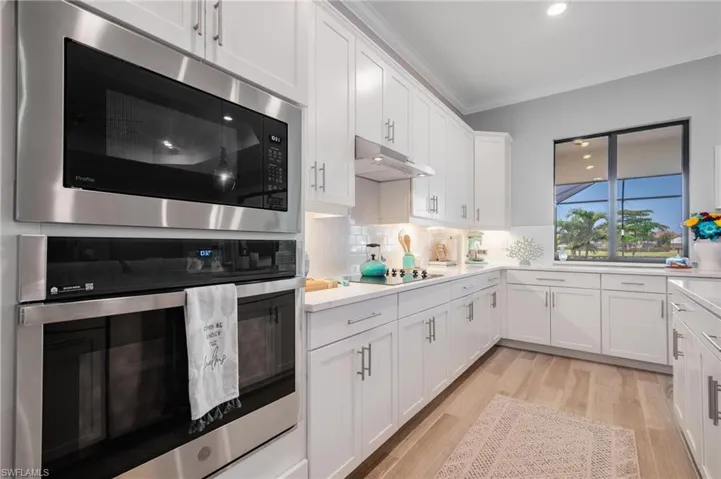 Kitchen featuring light hardwood / wood-style flooring, stainless steel appliances, crown molding, and white cabinetry