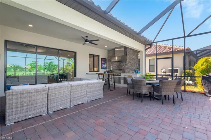 View of patio featuring an outdoor living space, ceiling fan, an outdoor kitchen, a grill, and a lanai