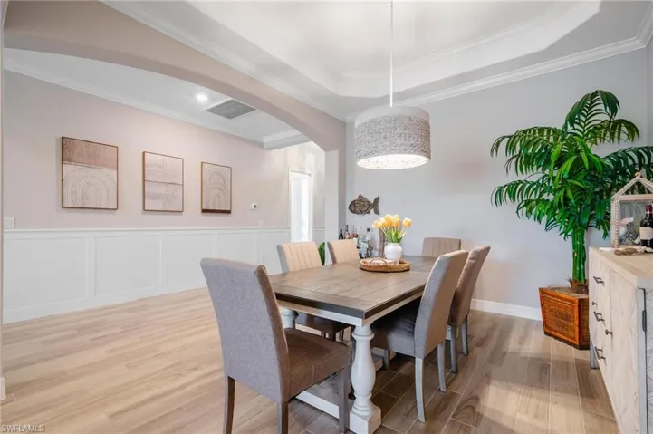 Dining area featuring ornamental molding, light wood-type flooring, and a tray ceiling