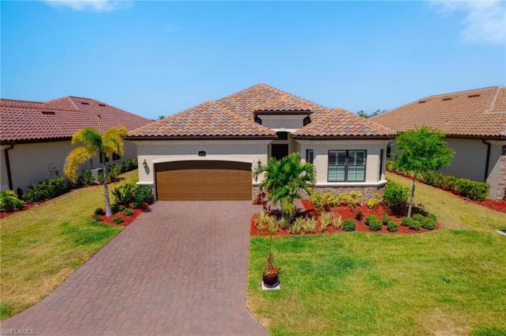 Mediterranean / spanish-style home with a garage and a front lawn