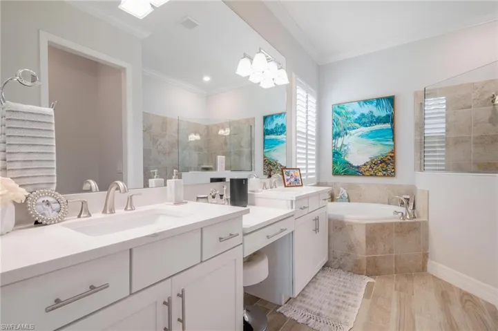 Bathroom featuring ornamental molding, hardwood / wood-style flooring, vanity, and plus walk in shower