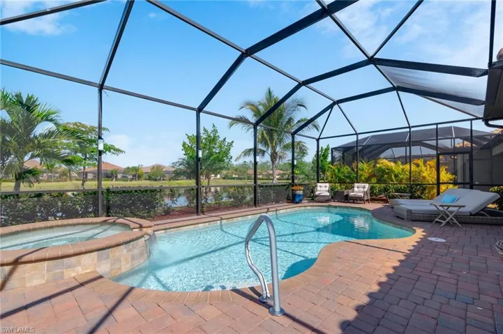 View of pool featuring a water view, an in ground hot tub, and glass enclosure