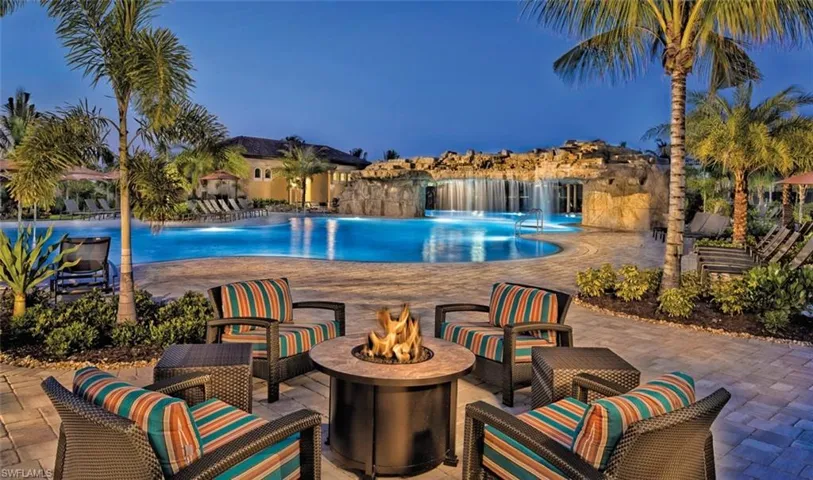 Pool at dusk with an outdoor fire pit, a patio area, and pool water feature