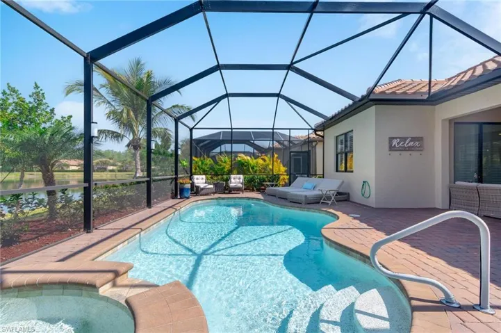 View of swimming pool featuring a water view, glass enclosure, a patio, and a hot tub