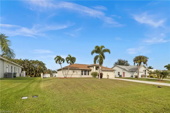 View of front of property featuring a garage, central air condition unit, and a front lawn