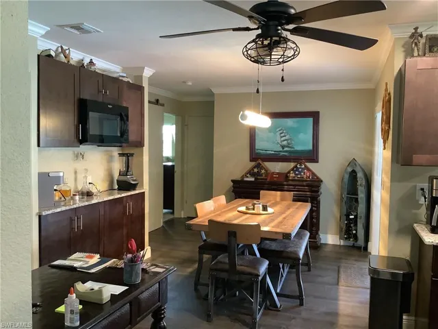 Dining area with crown molding, dark wood finished floors, and a ceiling fan