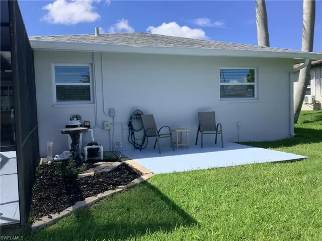 Rear view of property featuring a yard, a shingled roof, stucco siding, and a patio area