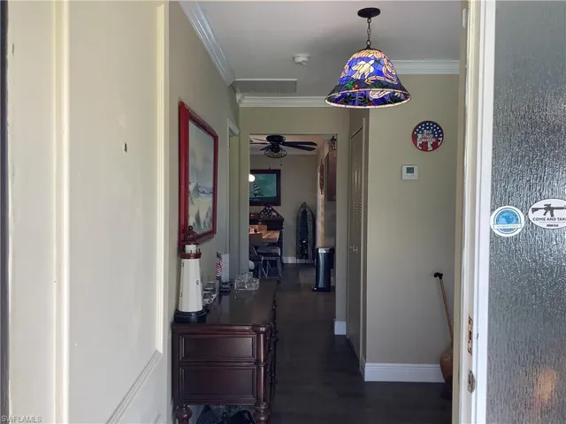 Hall with ornamental molding and dark wood finished floors