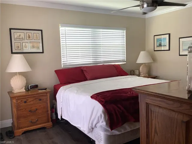 Bedroom with crown molding, a ceiling fan, and dark wood-style floors