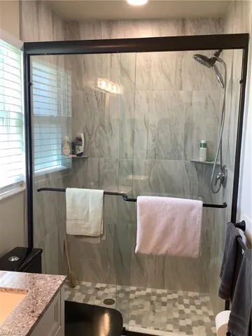 Bathroom with vanity and a marble finish shower