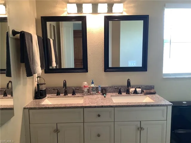 Full bathroom featuring double vanity and a textured wall