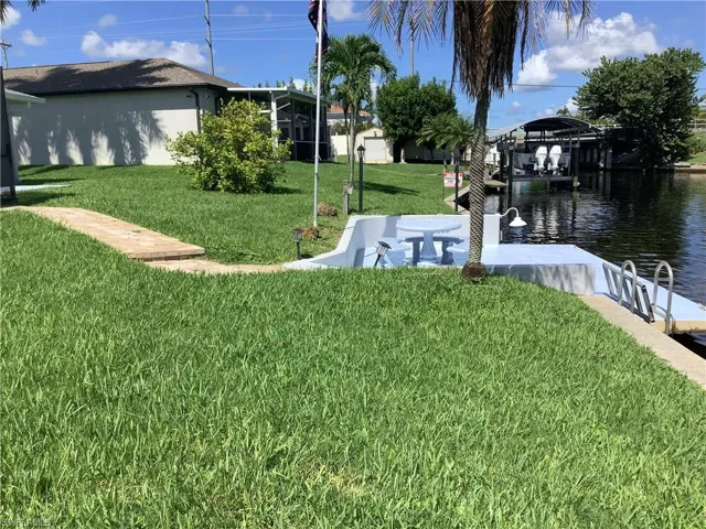 View of grassy yard with a water view and a boat dock