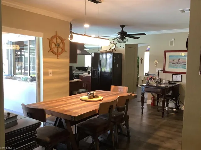 Dining room with crown molding, dark wood finished floors, and ceiling fan