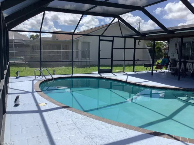 Outdoor pool with a sunroom, a patio, and glass enclosure