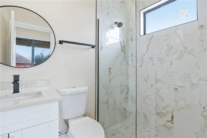 Efficiency bathroom featuring plenty of natural light, toilet, and vanity