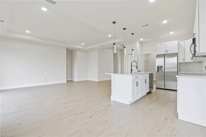 Kitchen with white cabinets, appliances with stainless steel finishes and a kitchen island with sink
