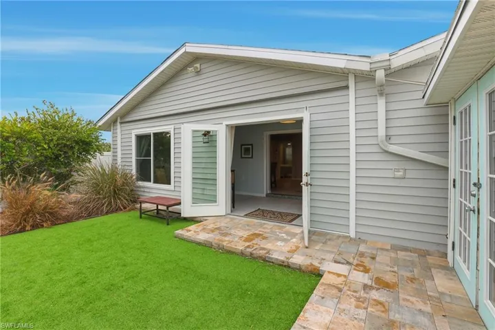View of exterior entry featuring a yard and a patio