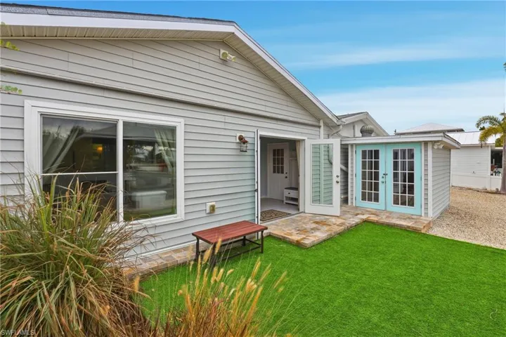 Rear view of house featuring french doors, a patio area, and a lawn