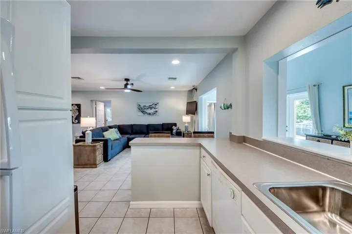 Kitchen with a ceiling fan, white appliances, light tile patterned floors, white cabinetry, and open floor plan