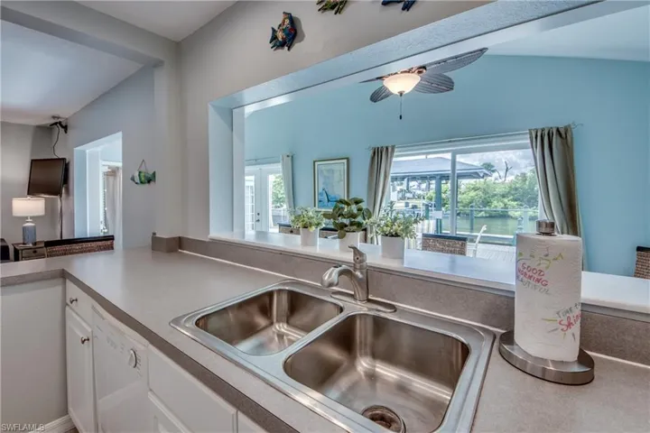 Kitchen featuring white cabinetry, white dishwasher, healthy amount of natural light, and a ceiling fan