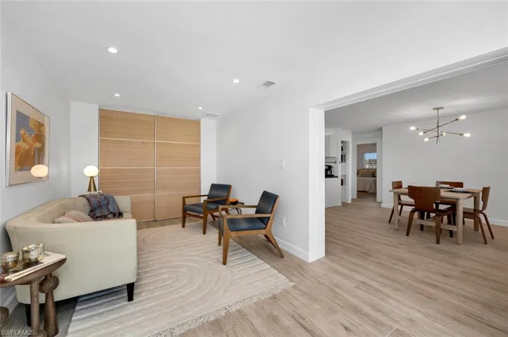 Den with light wood-style tile floors and an inviting chandelier