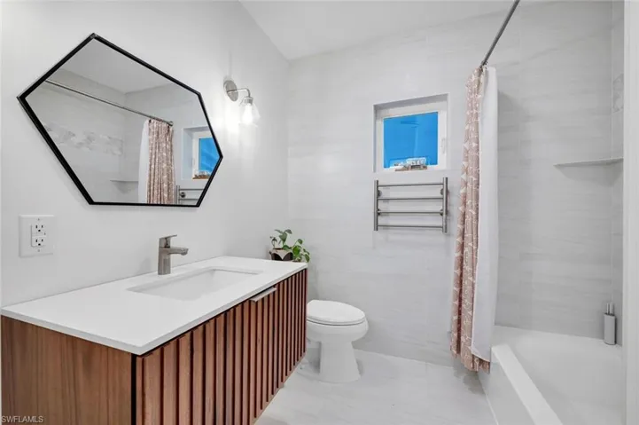 Full bathroom featuring vanity, toilet, tile walls, and shower / bath combo with shower curtain