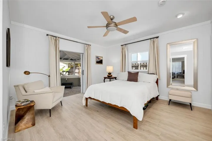 Bedroom with multiple windows, light wood-style tile flooring, ceiling fan, and ornamental molding