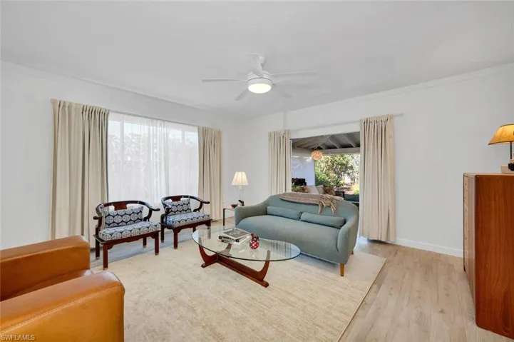 Living room with ceiling fan, light wood-style tile flooring, and crown molding
