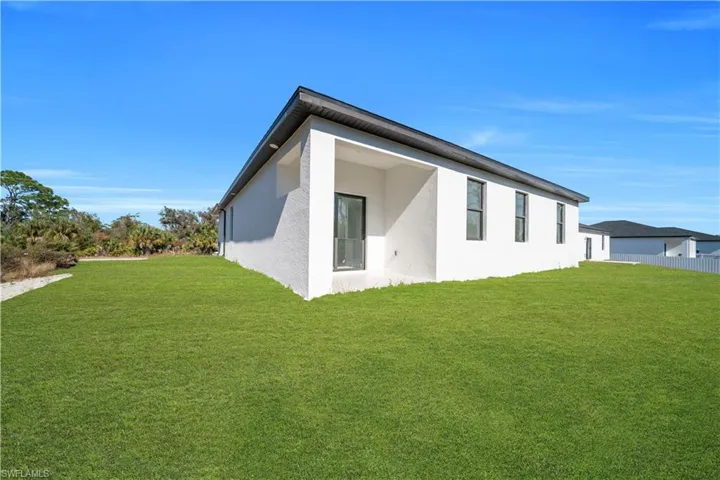 Rear view of property featuring a yard and stucco siding