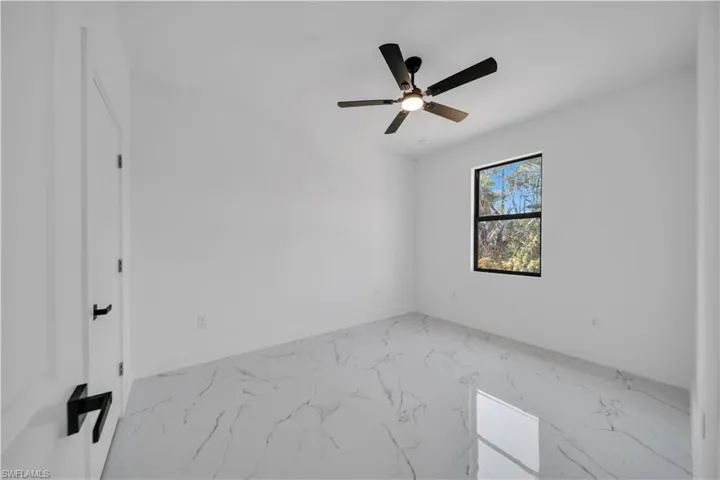 Spare room with marble finish flooring and a ceiling fan