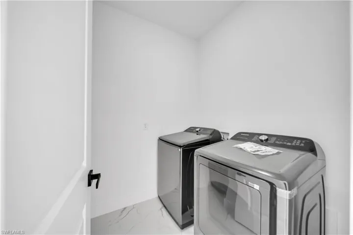 Laundry area with light marble finish flooring and separate washer and dryer