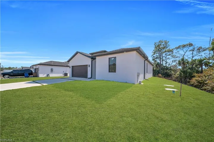 View of front facade with a front lawn, driveway, an attached garage, and stucco siding