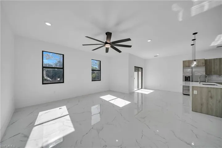 Unfurnished living room with recessed lighting, a ceiling fan, and light marble finish flooring