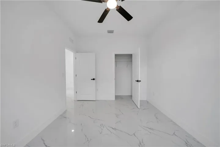 Unfurnished bedroom with light marble finish flooring, a ceiling fan, and a closet