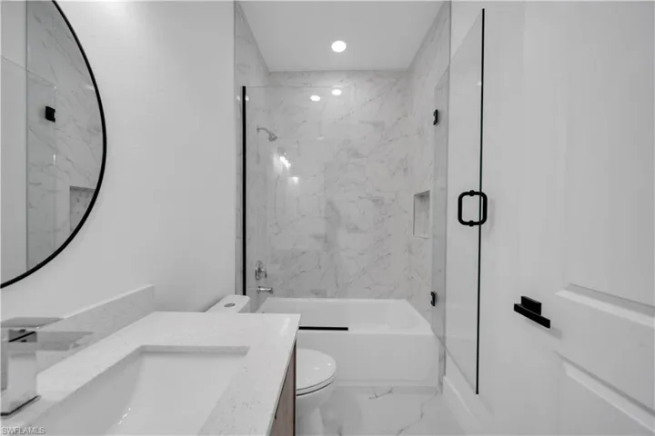Bathroom featuring marble look tile flooring, vanity, bath / shower combo with glass door, and recessed lighting
