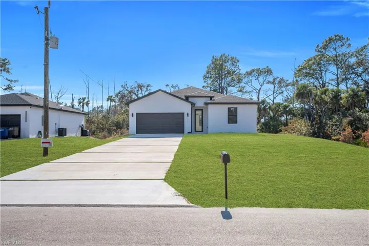 Ranch-style home with a front lawn, stucco siding, driveway, and a garage