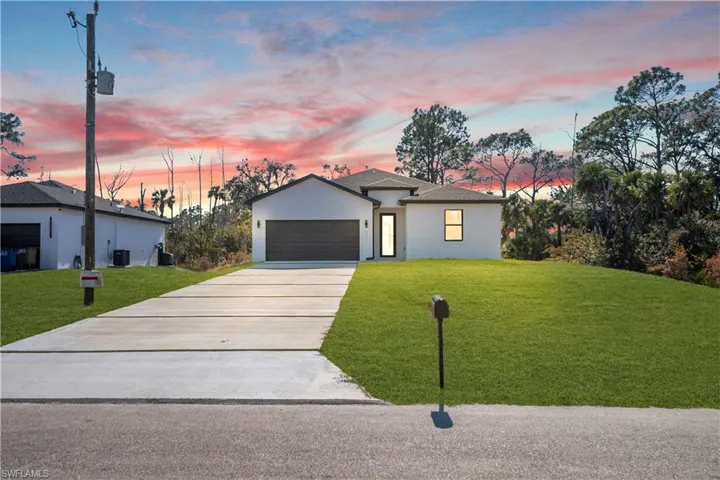 Single story home with a front yard, concrete driveway, stucco siding, and a garage