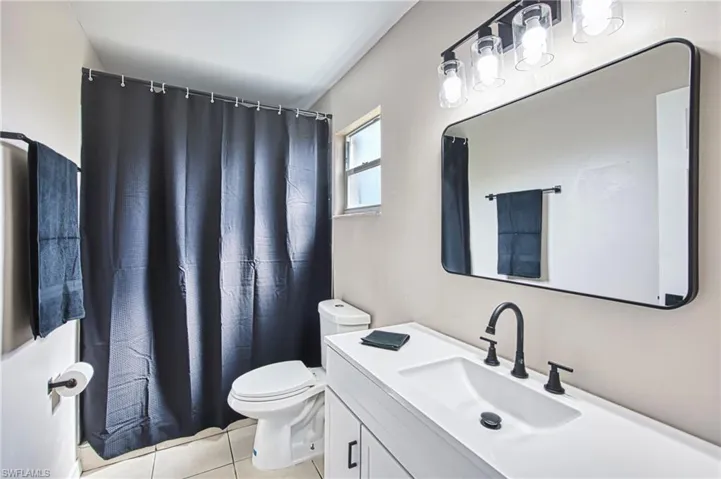 Full bath with a shower with curtain, vanity, and light tile patterned flooring