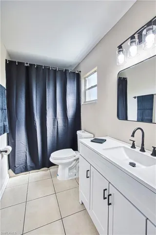 Full bath with a shower with curtain, vanity, and light tile patterned floors