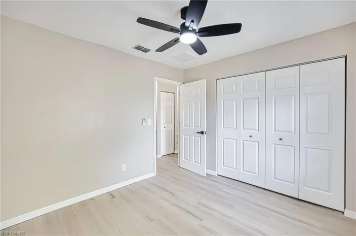 Unfurnished bedroom with light wood-style flooring, a ceiling fan, and a closet