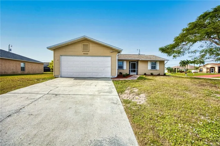 Ranch-style home featuring a front lawn and concrete driveway