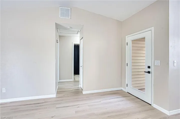 Spare room featuring light wood-type flooring, attic access, and lofted ceiling