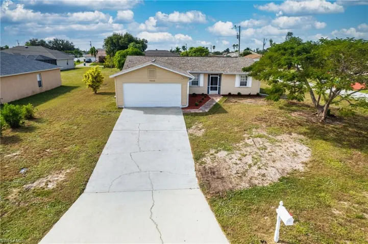 Ranch-style home with driveway, a front yard, and an attached garage