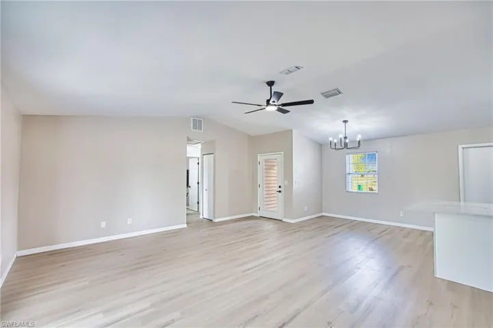 Unfurnished living room featuring light wood-style floors, a chandelier, a ceiling fan, and vaulted ceiling