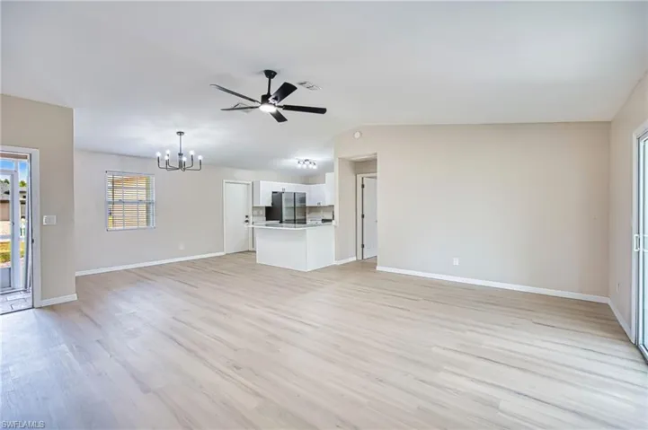 Unfurnished living room featuring light wood-style flooring, a chandelier, and ceiling fan