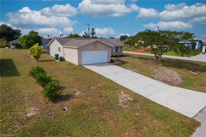 Ranch-style house with concrete driveway, a front yard, and an attached garage
