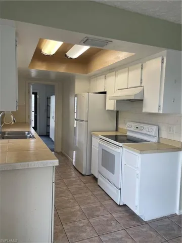 Kitchen with range, exhaust hood, tasteful backsplash, a sink, and light countertops