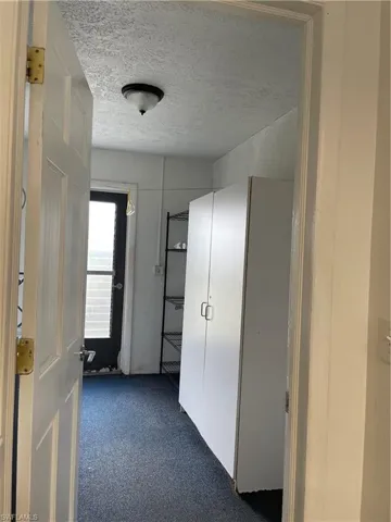 Corridor featuring dark carpet and a textured ceiling